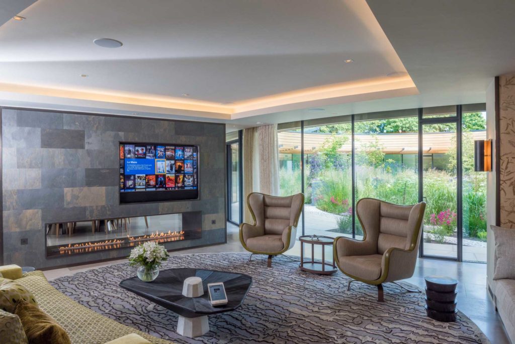 A contemporary living space with wall mounted television and surround sound system.
