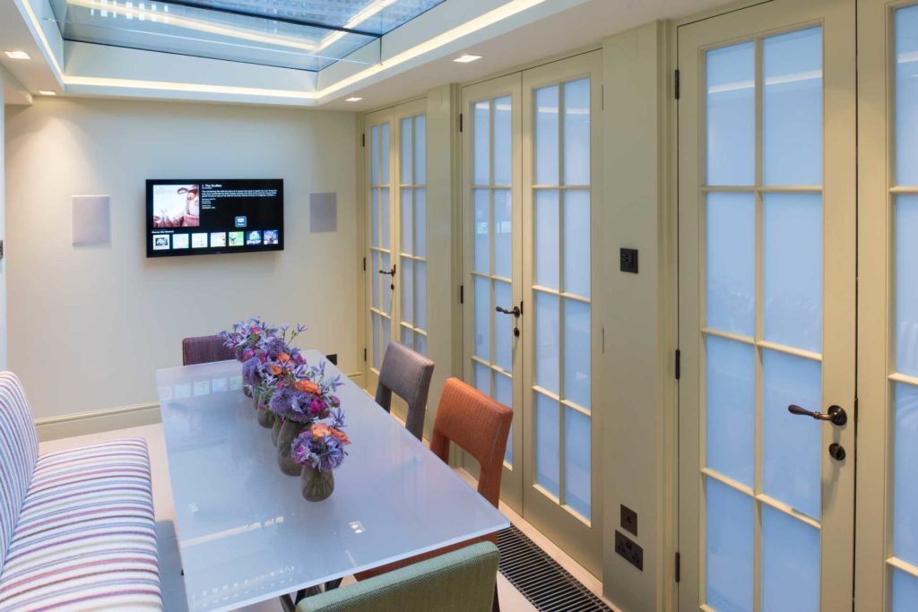 A dining room with wall mounted television, in-wall loudspeakers and lighting control.