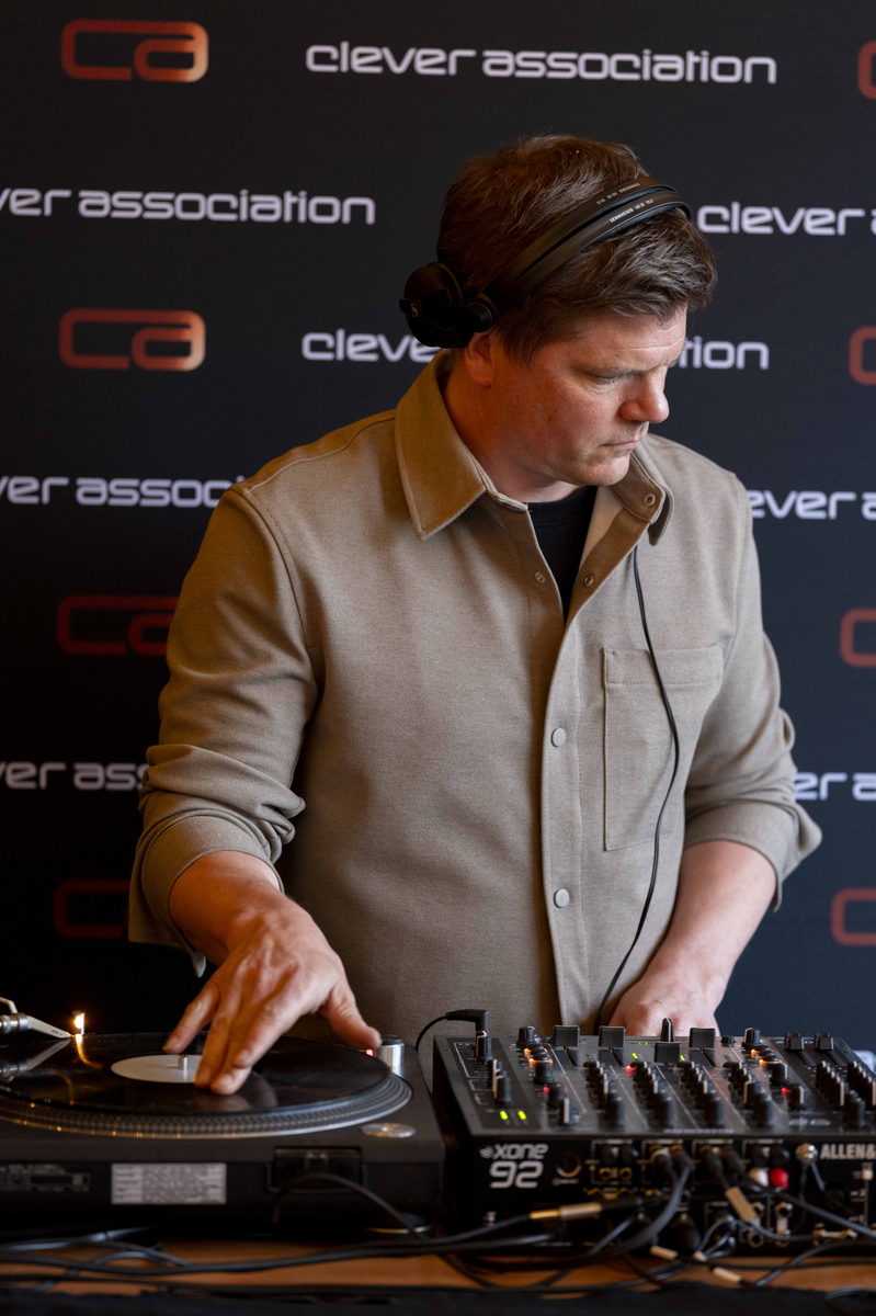 A DJ playing a set in front of the Clever Association backdrop